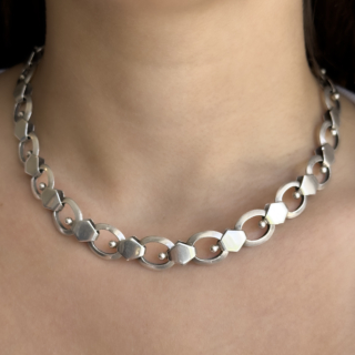 1938 Silver Link Necklace. A striking original Art Deco sterling silver necklace, hallmarked in London in 1938. The back also features a K.LTD makers mark. The necklace is composed of substantial circular links joined by geometric silver connectors, each accented with polished sphere details that perfectly capture the clean, architectural styling of the late Art Deco period. The bold design reflects the streamlined modernity that defined jewellery of the 1930s, balancing strong geometric forms with elegant movement and wearability. Beautifully constructed in solid sterling silver, the neck chain measures 18.5inches and weighs 48.6g. Increasingly sought after, pieces from this period embody a timeless sophistication that remains remarkably contemporary today. At the end of the chain there is a seamless bolt ring fastening. Please contact us if you would like to know more about this amazing chain or visit us at Saddingtons Jewellery, Mayfair.