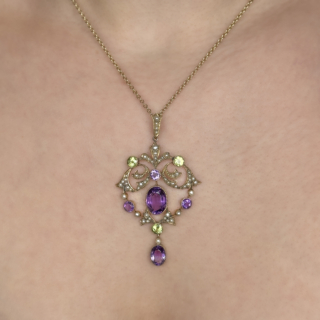 Exquisite and Significant Antique Suffragette Pendant. The Pendant is set with natural seed pearls, milgrain set peridot and amethysts all in an elaborate swirling pattern typical of the era in 15ct yellow gold. There is a rubover oval drop at the bottom of the pendant giving a gentle movement when wearing. There is a large seed pearl bale at the top of the pendant for a chain which is not provided with this pendant. The pendant measures 2.2 inches from the top of the bale to the bottom of the pendant and 1.5 inches wide. Please message us if you would like to purchase a chain.