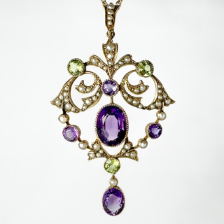 Exquisite and Significant Antique Suffragette Pendant. The Pendant is set with natural seed pearls, milgrain set peridot and amethysts all in an elaborate swirling pattern typical of the era in 15ct yellow gold. There is a rubover oval drop at the bottom of the pendant giving a gentle movement when wearing. There is a large seed pearl bale at the top of the pendant for a chain which is not provided with this pendant. The pendant measures 2.2 inches from the top of the bale to the bottom of the pendant and 1.5 inches wide. Please message us if you would like to purchase a chain.