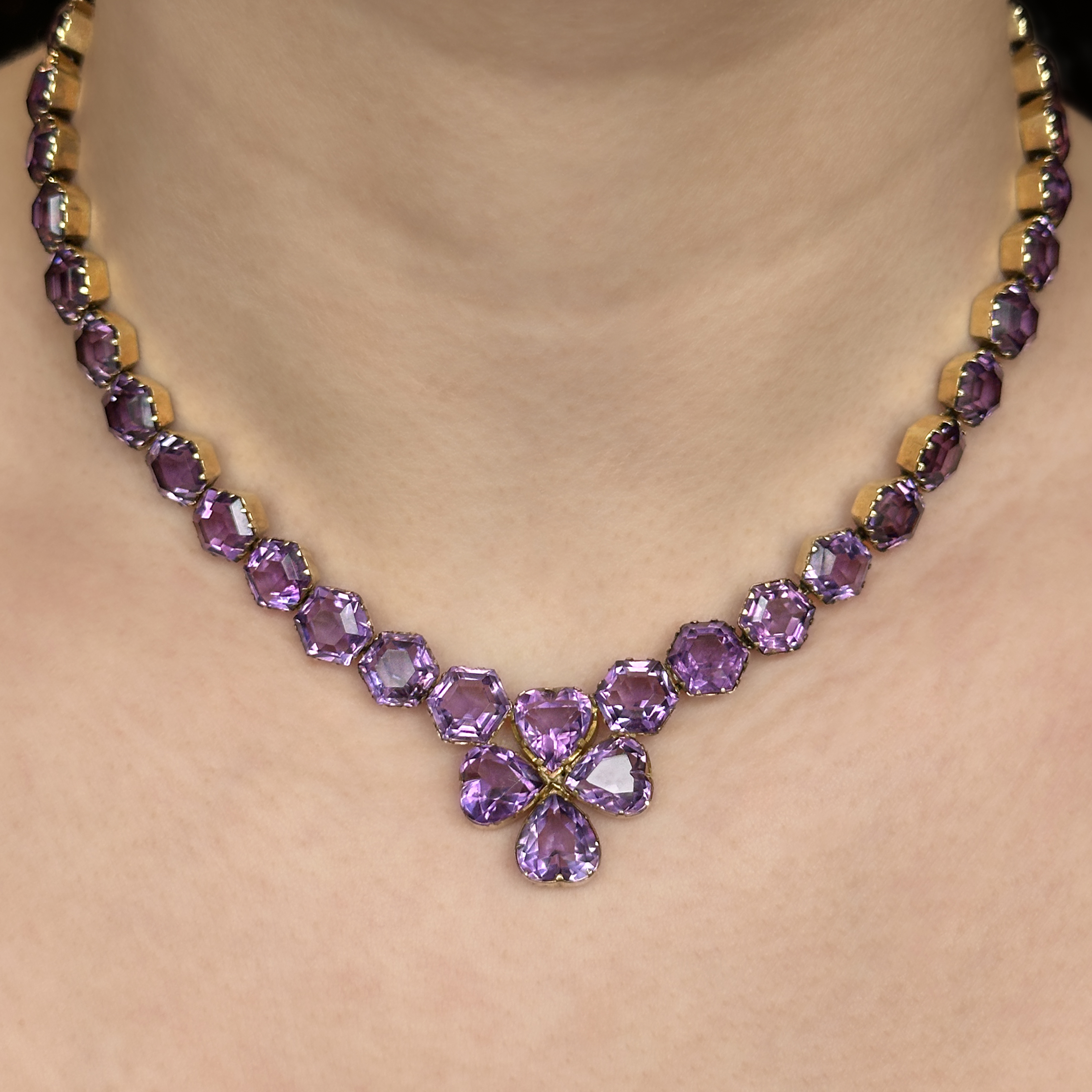 Beautiful Antique Victorian Amethyst Necklace. The hexagonal amethysts are collet claw set and linked, the necklace is flexible measuring 16 inches in total. Each amethyst measures 0.4 inches leading to a clover shaped amethyst heart made up of collet set heart shaped amethysts. The necklace has 40 rich purple amethysts in total including the securing clasp. There is a catch at the back of the necklace has a hexagonal collet set amethyst with a securing gold snap plate which has a 1.4 inch gold chain either side. A stunning antique and unique necklace. Please contact us if you would like to know more about this necklace or visit us at Saddingtons Jewellery, Mayfair.