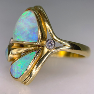 Fancy Asymmetric Water Opal and Diamond Ring in 18ct Yellow Gold, Hallmarked London, 1963. The unusual vintage custom made ring holds three vibrant water opals, two are of asymmetric shape, one circular. The opals are a mesmerising turquoise blue and purple with hints of green and yellow, we would even go as far as saying the colours are fluorescent. The split shoulders are decorated with two brilliant cut diamonds, of different cartage. The total head of the ring measures approximately 21.8 mm x 17 mm, The depth of the head 7 mm approximately. All the stones are bezel set in a half round polished shank. This ring is in immaculate condition, the opal will be professionally polished before any purchase. 