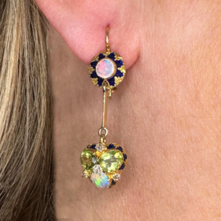 Stunning Antique Opal Peridot Diamond Enamel Drop Earrings set with Diamonds in a cluster setting. Truly unique and beautiful earrings. The drop from the ear 3.5cm with a shepards crook French wire safety hook in 15ct yellow gold. The top of the earring has intricate fancy enamel with vibrant colourful white opals. The drop has a vibrant and unusual cluster set with two peridots and a white opal. Four small old cut diamonds adding sparkle. Contact us for any further information. 