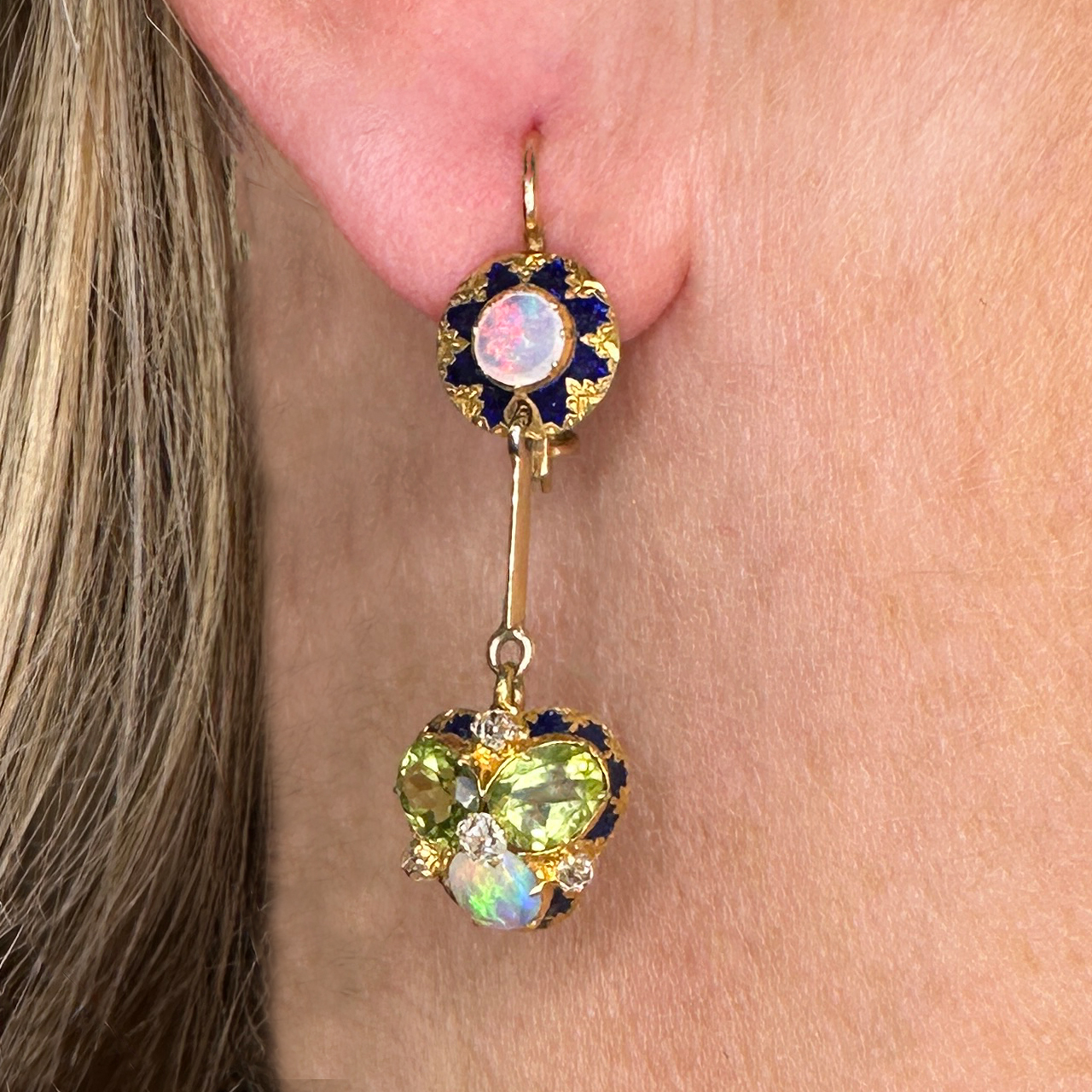 Stunning Antique Opal Peridot Diamond Enamel Drop Earrings set with Diamonds in a cluster setting. Truly unique and beautiful earrings. The drop from the ear 3.5cm with a shepards crook French wire safety hook in 15ct yellow gold. The top of the earring has intricate fancy enamel with vibrant colourful white opals. The drop has a vibrant and unusual cluster set with two peridots and a white opal. Four small old cut diamonds adding sparkle. Contact us for any further information.