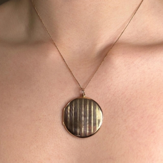 Beautiful antique Edwardian 15ct yellow gold large circular locket. The locket has a vertical line pattern on the front of the locket, a typical style from the Edwardian era. There is a substantial bale allowing varying chain sizes to be worn. The back of the locket is plain gleaming gold with the hallmark and makers mark partially worn. The locket opens with a strong hinge in good order, there is also a bezel inside to secure a photo keepsake. The locket is 3cm diameter and is slim and elegant 3mm width. Please contact us for more information. Type Pendant Era Edwardian Gold Carat 15ct Material Yellow Gold Weight 8.5g Year Circa 1910