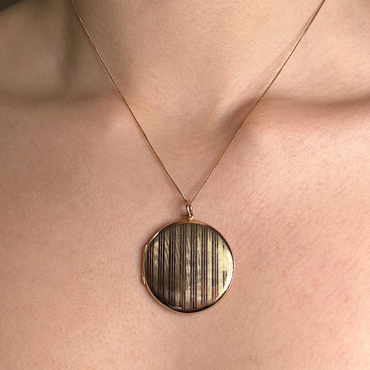 Beautiful antique Edwardian 15ct yellow gold large circular locket. The locket has a vertical line pattern on the front of the locket, a typical style from the Edwardian era. There is a substantial bale allowing varying chain sizes to be worn. The back of the locket is plain gleaming gold with the hallmark and makers mark partially worn. The locket opens with a strong hinge in good order, there is also a bezel inside to secure a photo keepsake. The locket is 3cm diameter and is slim and elegant 3mm width. Please contact us for more information. Type Pendant Era Edwardian Gold Carat 15ct Material Yellow Gold Weight 8.5g Year Circa 1910