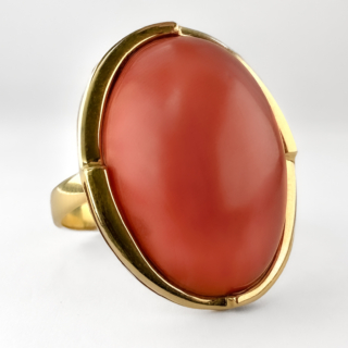 Elegant Large Coral Cabochon Statement Ring . This amazing vibrant and smooth opaque orange-red mediterranean precious coral stone is set in 18ct yellow gold. The mount is a sleek and sculptural double layered design complementing the stone beautifully. On the underside there is an Italian hallmark with a Napoli NA stamp and makers registration as well as an 18ct hallmark. The top measures 2.5cm and the ring can be resized. This vintage ring makes for the perfect statement ring and sits comfortably on the finger. Please contact us if you would like to know more about this amazing ring or visit us at Saddingtons Jewellery, Mayfair.