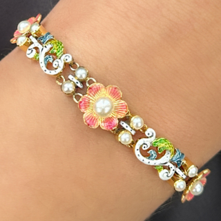 Unusual and Pristine Antique Flower Pearl and Enamel Bracelet.Three enamelled pink flowers each with a central natural pearl.On each side of the central flower there are two white,green and blue enamelled scrolling flowers and leaves.Between each of the enamelled flowers and enamelled flower scrolls there are four sets of two rub over set natural pearl spacers.The bracelet has curb link chain in 15ct yellow gold total length 6.8inches with a safety chain attached but can be removed if desired.The securing fitting is a snap catch/plate.This bracelet is unique and beautiful and in excellent condition.Please contact us if you would like to know mor