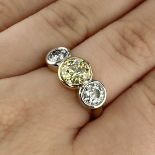 Stunning Edwardian Yellow and White Diamond 3 Stone Ring. This impressive 3 stone ring features a central natural fancy yellow 1.25ct diamond with 2 white diamonds totalling 1.14cts either side. The two white diamonds are G-H in colour and VS1 clarity. All 3 stones are transitional brilliant cut diamonds and are bezel set in 18ct yellow gold. The yellow diamond is VS1 clarity and comes with a cert. This ring sits beautifully and comfortably on the finger. Please contact us if you would like to know more about this amazing ring or visit us at Saddingtons Jewellery, Mayfair.