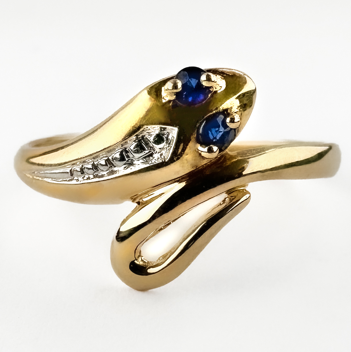 Pretty Sapphire Eyes Gold Snake Ring. This sweet small snake gold ring features two deep blue sapphires for its eyes. The ring is 18ct yellow old and has detailing down its back. This ring can be resized. Please contact us if you would like to know more about this beautiful ring or visit us at Saddingtons Jewellery, Mayfair.