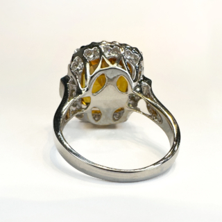 Beautiful Glowing 7ct Orange Yellow Sapphire Cluster Ring.Set in 18ct white gold with a large square cushion cut sapphire surrounded over 1ct of brilliant cut and emerald cut diamonds G-H colour and VS clarity.All stones are claw set except the 3 emerald cut diamonds on each side of the shoulders.The shank is marked 750 (18ct).Size M1/2 in UK sizing but can be resized.Please contact us if you would like further information on this stunning ring.