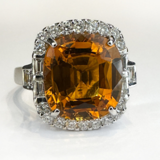 Beautiful Glowing 7ct Orange Yellow Sapphire Cluster Ring.Set in 18ct white gold with a large square cushion cut sapphire surrounded over 1ct of brilliant cut and emerald cut diamonds G-H colour and VS clarity.All stones are claw set except the 3 emerald cut diamonds on each side of the shoulders.The shank is marked 750 (18ct).Size M1/2 in UK sizing but can be resized.Please contact us if you would like further information on this stunning ring.