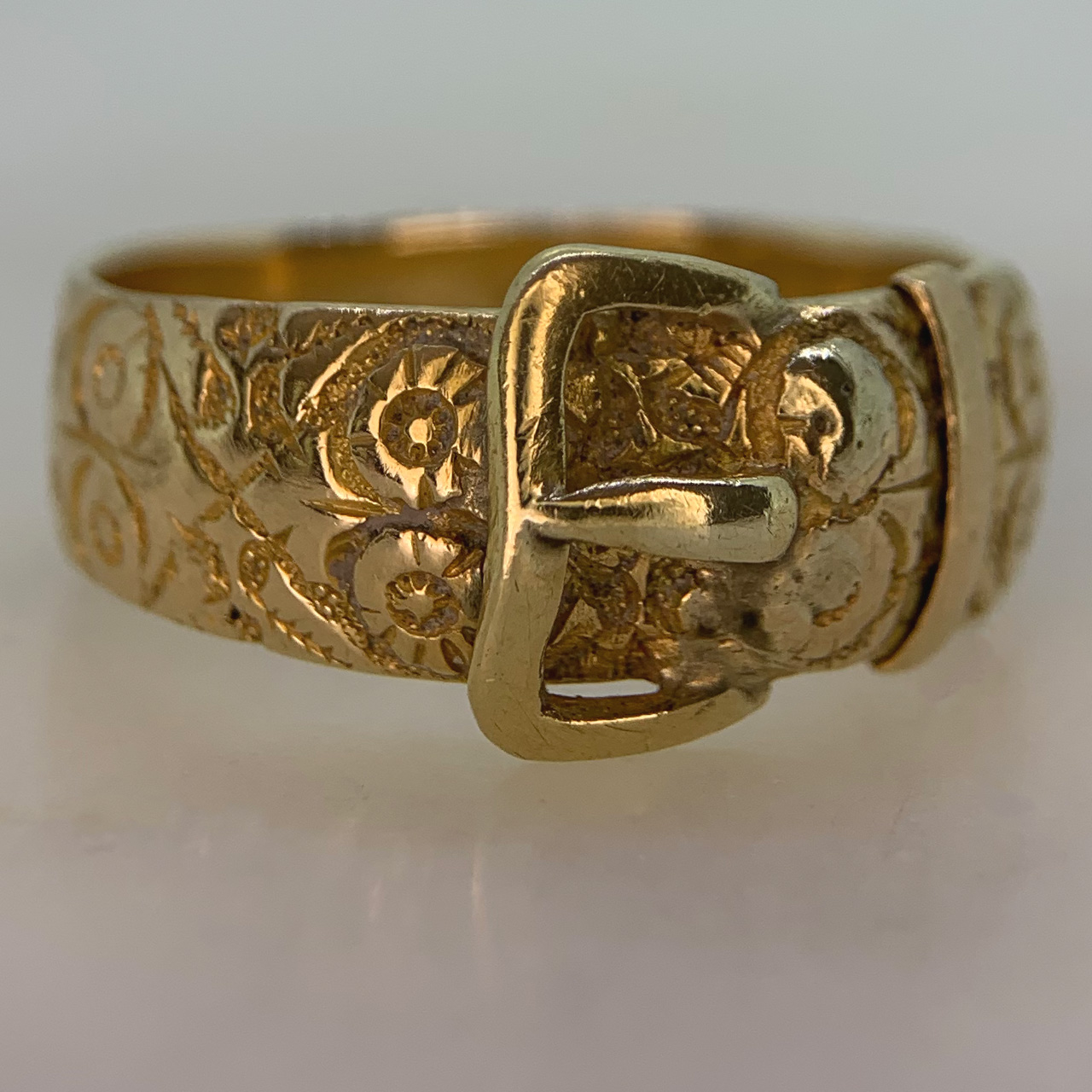 Stunning Rose Vine Chased Buckle Ring in 18ct Yellow Gold, Hallmarked Birmingham, 1887. The ring is decorated with roses and thorns, the buckle itself and the inner shank is polished, it is likely the roses signify the year of Queen Victorias Golden Jubilee. The buckle width is 11 mm and the band width measures 8 mm. The ring tapers towards the back, the back of the ring is slightly worn, with the rose detailing rubbed off, however overall an excellent antique ring in good condition. The date of this ring correlates to Queen Victorias Golden Jubilee.  