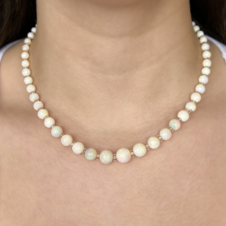 Pretty Edwardian Opal Beaded Necklace. This beautiful graduated spherical opal bead necklace features 60 white opals with rock crystal roundel spacers, except from the last 2 inches on either side. The necklace measures 17 inches. The biggest opal measures 10.3mm and the smallest is 3.8mm. The white gold clasp has 13 small diamonds set into it and also features a makers mark. Please contact us if you would like to know more about this necklace or visit at Saddingtons Jewellery, Mayfair.