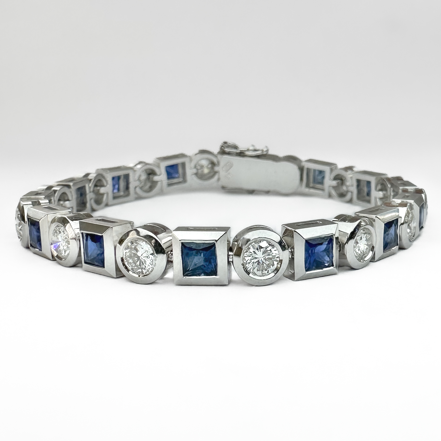 Exquisite 1950's Sapphire & Diamond Bracelet. This is a stunning 18ct white gold bracelet set with alternating round diamonds and square sapphires, in total there are 14 sapphire and 14 diamonds. The diamonds are brilliant cut and the sapphires are princess cut, all stones are in rub over settings. Each diamond weighs 0.25cts, in total the diamond weight is 3.5cts. The sapphires weigh 0.3cts each, totalling to 4.2cts. This bracelet is robust, well made and flexible therefore is very comfortable on the wrist. The bracelet weighs 31.9 grams and measures at 6.9 inches in length. It also features an 18ct stamp as well as a marker mark 'ifau'. Please contact us if you would like to know more about this bracelet or visit us at Saddingtons Jewellery, Mayfair.