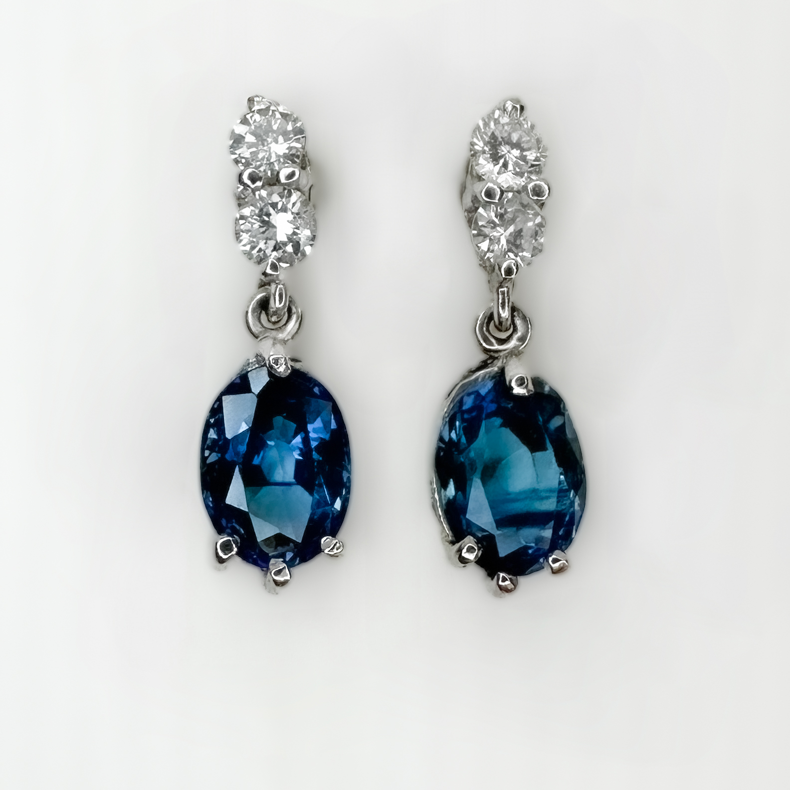 Exquisite Sapphire & Diamond Drop Earrings.Beautiful natural sapphire and diamonds claw set in 18ct white gold with a securing platinum butterfly.The earrings have 2 sparkling bright diamonds dropping to the midnight blue sapphire.The total drop of the earrings from the diamond stud to the bottom of the sapphire is 1.8cm.Please contact us if you would like further information on these earrings.