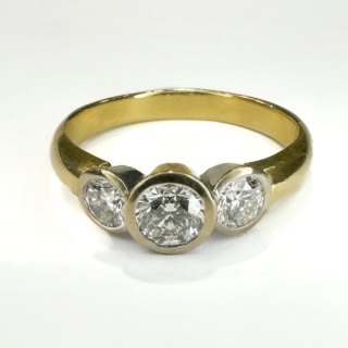Modern Brilliant Cut Diamond Rub Over Trilogy Ring.Total diamond weight 0.80ct,the diamonds G-H colour and /clarity VVS, set in an 18ct yellow gold shank with the diamonds set in platinum.The width of the head of the ring on the finger 1.5cm and 0.5 across.There is a Birmingham 750 hallmark inside the shank with additional 18ct mark.The ring sits comfortable and low on the finger.A beautiful yet simple ring design with 3 bright sparkling diamonds.The ring is UK size N1/2 and can be resized preserving the hallmarks.Please contact us if you would like to know more about this ring.