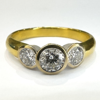 Modern Brilliant Cut Diamond Rub Over Trilogy Ring.Total diamond weight 0.80ct,the diamonds G-H colour and /clarity VVS, set in an 18ct yellow gold shank with the diamonds set in platinum.The width of the head of the ring on the finger 1.5cm and 0.5 across.There is a Birmingham 750 hallmark inside the shank with additional 18ct mark.The ring sits comfortable and low on the finger.A beautiful yet simple ring design with 3 bright sparkling diamonds.The ring is UK size N1/2 and can be resized preserving the hallmarks.Please contact us if you would like to know more about this ring.