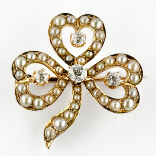 Edwardian Pearl & Diamond Clover Brooch. Stunning clover brooch with 42 pearls and 4 diamond set in 15ct yellow gold. The leaf heart shape sections have 12 pearls with a small transitional brilliant cut diamond claw set in the centre, the biggest diamond sits in the middle of the clover design. The openwork design creates a delicate lightness typical of refined late Victorian and Edwardian jewellery. Rich in symbolism, clover jewellery traditionally represented luck, hope, faith and love, making pieces such as this highly cherished sentimental gifts during the Victorian era. The soft glow of the pearls contrasts beautifully with the lively brilliance of the diamonds, creating an elegant and timeless composition.From top to bottom the brooch measures 2.8cm and it is 2.6cm wide. Please contact us if you would like to know more about this wonderful brooch or visit us at Saddingtons Jewellery, Mayfair.