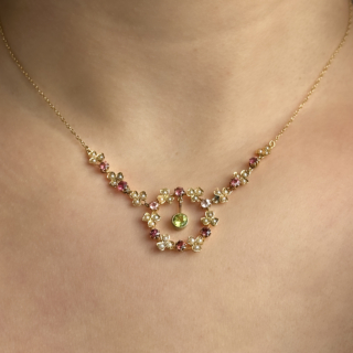 Gorgeous Edwardian Peridot Tourmaline & Pearl Festoon Necklace. A beautifully delicate antique Edwardian festoon necklace set with peridot, pink tourmaline and seed pearls in 15ct yellow gold. Designed in an elegant garland style, the necklace features fine floral-inspired clusters of lustrous seed pearls interspersed with vivid pink tourmalines, leading to a suspended green peridot drop at the centre. The openwork festoon design creates graceful movement and beautifully reflects the light when worn. Light and feminine in character, the necklace embodies the refined romanticism Edwardian jewellery design, where floral motifs, soft colour palettes and delicate gemstone combinations were highly fashionable. Elegant at the collarbone, it pairs beautifully with both contemporary and period-inspired styling. The necklace measures 37.5cm long. Please contact us if you would like to know more about this stunning necklace or visit us at Saddingtons Jewellery, Mayfair.