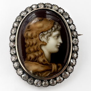 Victorian Diamond & Enamel Hercules Portrait Brooch. An exceptional antique late Victorian classical portrait brooch, centred with an enamel plaque depicting a heroic Greco-Roman male profile traditionally identified as Hercules. Rendered in rich sepia and ivory tones, the finely detailed portrait displays strong Neo-Classical influence, inspired by ancient Roman and Grand Tour artistic traditions so admired during the 19th century. The oval portrait plaque is framed by a glittering border of 33 old-cut diamonds, totalling to 1ct in a silver-topped gold setting, creating beautiful contrast and soft antique brilliance. The brooch measures 2.8cm x 2.2cm. Pieces of this nature were often collected as expressions of education, travel and appreciation for antiquity. This piece comes in the box pictured. Please contact us if you would like to know more about this wonderful brooch or visit us at Saddingtons Jewellery, Mayfair.