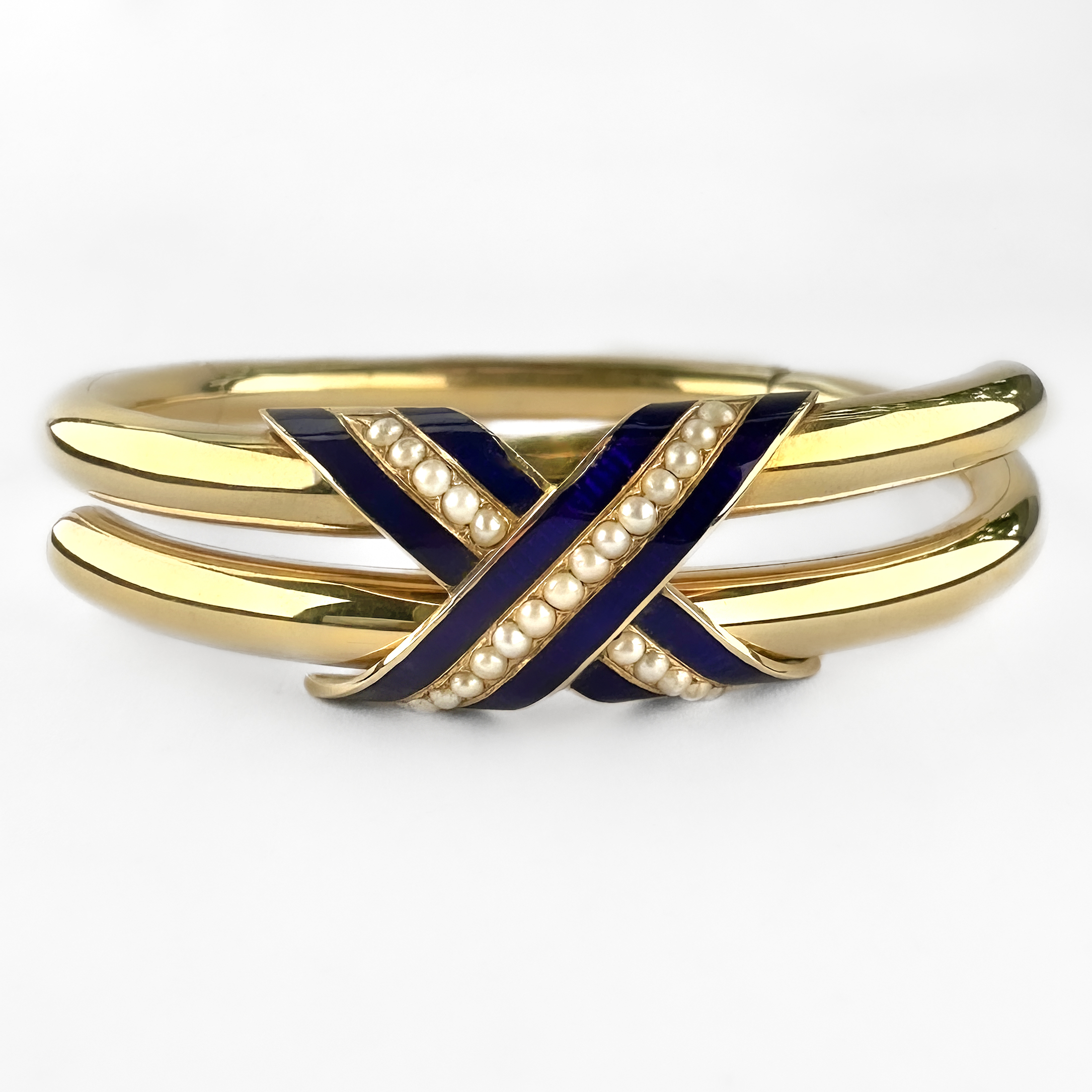 Lovely Victorian Gold Enamel & Pearl Bangle. A beautifully elegant antique Victorian 15ct gold blue enamel and seed pearl hinged bangle, internally engraved and dated. This refined mid-Victorian bangle is designed with a graceful crossover motif, decorated with rich royal blue enamel and delicate rows of graduating seed pearls. The smooth tubular gold construction gives the piece an understated sophistication, while the vivid enamelwork provides striking contrast against the warm tones of the gold. The bangle opens via a discreet concealed hinge and integrated clasp typical of fine Victorian jewellery craftsmanship. Jewellery of this period often carried symbolic meaning, with blue enamel traditionally associated with loyalty and devotion, and seed pearls representing purity and affection. The engraving inside reads 'S C E C and Ruthie' '24th August 1854'. The inscription adds a wonderful sense of romance and authenticity, preserving the personal history of the piece. Elegant and highly wearable, the bangle sits beautifully on the wrist and transitions effortlessly from daywear to evening styling. It may be worn alone as a refined antique statement piece or layered with contemporary gold jewellery for a more modern aesthetic. The piece weighs 17.5g. Please contact us if you would like to know more about these stunning earrings or visit us at Saddingtons Jewellery, Mayfair.