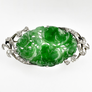 Lovely Vintage Jade & Diamond Brooch. An exceptional vintage 1930/40's natural untreated jade and diamond brooch, centred with a beautifully hand-carved plaque of vivid emerald-green jade and fine natural translucency. The jade is intricately carved with traditional floral and foliate motifs, symbols long associated in Chinese culture with prosperity, harmony and longevity. Framed within an elegant diamond-set 18ct white gold mount, the brooch combines refined Eastern craftsmanship with sophisticated Art Deco-inspired Western design. The richly saturated jade displays the highly prized luminous quality. Surrounding the carving are delicately set diamonds arranged in graceful ribbon and scroll motifs, adding brilliance without detracting from the beauty of the jade itself. The brooch measures 2.3cmx5.2cm. The perfect added detail bringing elegance to evening or casual wear. Please contact us if you would like to know more about this beautiful brooch or visit us at Saddingtons Jewellery, Mayfair.
