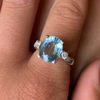 Exquisite Outsized Aquamarine and Diamond Trilogy Ring, in stamped 18ct White Gold. The centre aquamarine measures 3.8carats, enclosed by two diamonds. All the stones are claw set and measure 16 mm x 12 mm together, with a basket depth of 7 mm. The ring has a stylish flat-sided court shank, with a sort of square outer appearance. Excellent ring.