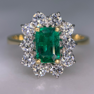 Outstanding Emerald and Diamond Rectangular Cluster Ring in 18ct Yellow Gold, Hallmarked London, 1990. The exquisite ring has a 1.4carat immaculate glowing emerald as a centre stone, surrounded by 1.02carats of brilliant cut, bright white diamonds (total diamond weight). All the stones are claw set in a platinum basket, with a reverse taper, raised flat band shank. The head of the ring measures approximately 14 mm x 12.5 mm. The ring is in absolutely immaculate condition.