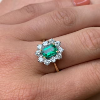 Outstanding Emerald and Diamond Rectangular Cluster Ring in 18ct Yellow Gold, Hallmarked London, 1990. The exquisite ring has a 1.4carat immaculate glowing emerald as a centre stone, surrounded by 1.02carats of brilliant cut, bright white diamonds (total diamond weight). All the stones are claw set in a platinum basket, with a reverse taper, raised flat band shank. The head of the ring measures approximately 14 mm x 12.5 mm. The ring is in absolutely immaculate condition.