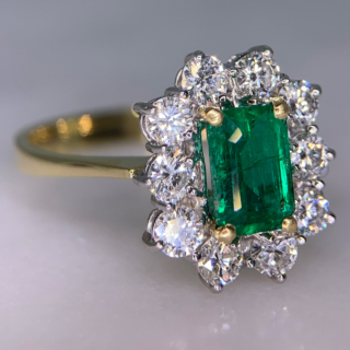 Outstanding Emerald and Diamond Rectangular Cluster Ring in 18ct Yellow Gold, Hallmarked London, 1990. The exquisite ring has a 1.4carat immaculate glowing emerald as a centre stone, surrounded by 1.02carats of brilliant cut, bright white diamonds (total diamond weight). All the stones are claw set in a platinum basket, with a reverse taper, raised flat band shank. The head of the ring measures approximately 14 mm x 12.5 mm. The ring is in absolutely immaculate condition.