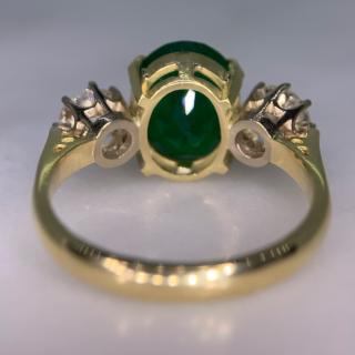 Exquisite Emerald and Diamond Trilogy Ring, in 18ct hallmarked yellow Gold, Birmingham 1996.  The centre deep emerald measures  11 mm x 9 mm and is enclosed by two diamonds totalling at 1.10carats of diamond weight. The total ring head measures 20 mm in width. All the stones are claw set with a basket depth of 6mm. The shank is polished with tiffany shoulders.  Excellent ring.