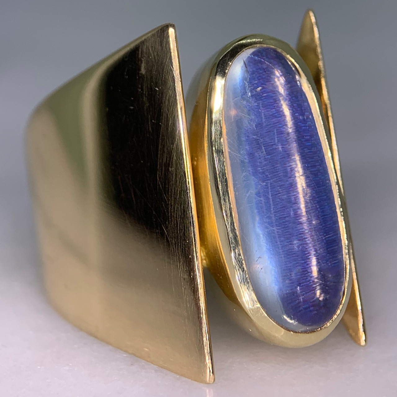 Unusual Brutalist Geometric Solitaire Moonstone Ring, stamped 750 (18ct) Yellow Gold. The exquisite ring has a 16 mm x 7 mm statement oval moonstone. The up-finger design of the ring shows an oval moonstone, bezel set, in yellow gold, with two geometric wide shoulders that taper to the back of the shank. The head measures approximately 21 mm x 11 mm, and tapers to 5 mm at the back of the ring. The ring is in absolutely immaculate condition and is a clear statement piece, great worn alone or in addition to other up-finger rings. 