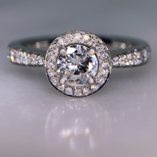 Incredible Diamond Halo Cluster Ring in 950 Platinum. The exquisite halo ring has a 0.63carat centre diamond, claw set with diamond halo. The head of the ring measures 9 mm in diameter with 12 diamond embellished shoulders. The ring has a flat sided-court shank, polished. All the stones are claw set. The ring is in absolutely immaculate condition.