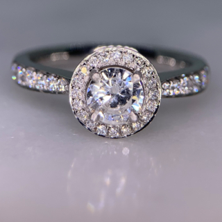 Incredible Diamond Halo Cluster Ring in 950 Platinum. The exquisite halo ring has a 0.63carat centre diamond, claw set with diamond halo. The head of the ring measures 9 mm in diameter with 12 diamond embellished shoulders. The ring has a flat sided-court shank, polished. All the stones are claw set. The ring is in absolutely immaculate condition.
