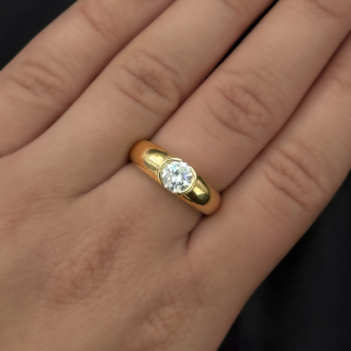 Chunky 1ct Diamond Solitaire Band Ring.A stunning and bright brilliant cut diamond centrally set in rub over setting in 18ct yellow gold.A vintage ring,'750' marked inside the shank denoting 18ct gold.the central diamond measures 0.6cm diameter.The Shank has a polished finish and measures 0.6cm at the widest where the diamond is set and gradually tapers to the back of the ring.The ring is comfortable to wear, low on the finger.It can be resized,please contact us if you would like to know more about this ring.