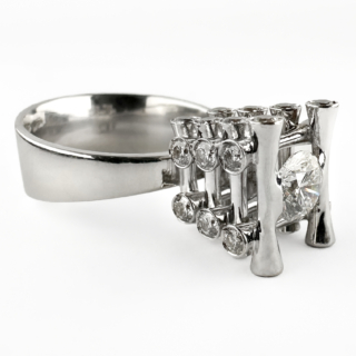 Marco Oldani For John Rasmussen Diamond Tower Ring. A remarkable contemporary diamond ring by Marco Oldani for respected danish jeweller John Rasmussen based in Limone Italy. It is crafted in 18ct white gold and showcasing approximately 1.50cts of diamonds in an eye-catching architectural tower design. At the centre of the ring sits a superb 0.60ct round brilliant-cut diamond, E in colour and VS2 clarity. This exceptional diamond is elevated within the design, drawing the eye immediately to its impressive brilliance and fire. Surrounding the centre stone are twenty-eight additional diamonds with a combined weight of approximately 0.90cts, creating a dazzling display of light from every angle. The sculptural tower setting is a distinctive feature of the design, giving the ring a strong contemporary aesthetic while maintaining the timeless appeal of fine diamond jewellery. Signed 'Oldani' to the shank, inside the shank is also 750 carat stamp as well as MU-56. The ring also has a 750 gold stamp on the back of the shank. Substantial in both weight (9.1g) and presence, the ring is beautifully crafted in 18ct white gold and offers an unusual alternative to more conventional diamond cluster or solitaire designs. The tower has a hight of 1cm from the base to the top. Its architectural styling makes it an ideal choice for those seeking a statement diamond ring with individuality. The ring comes with a Certification. Please contact us if you would like to know more about this brilliant signet ring or visit us at Saddingtons Jewellery, Mayfair.