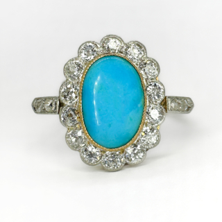 An Oval Antique Turquoise & Diamond Cluster Ring.The ring shank is in 18ct yellow gold with the diamonds set in platinum.A vibrant natural blue turquoise central oval stone surrounded by beautiful bright transitional cut diamonds additionally there are x2 diamonds set on each side of the shoulders of the ring, a total diamond content 1ct.The top of the ring measures 15 x 12mm.The ring is set low and sits comfortable on the finger.This ring can be resized,please contact us if you would like to know more about this ring.