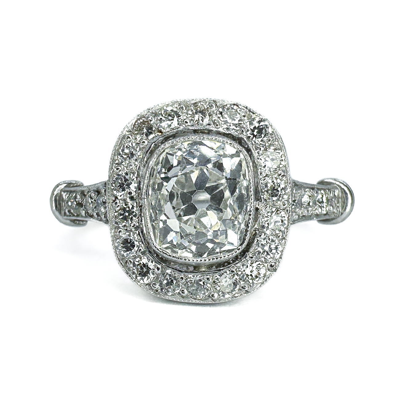 Antique Deco 1ct Old Cut Diamond Cluster Ring.The ring has a platinum shank,the central diamond is a Victorian cushion old cut diamond 1ct,colour H-I,Clarity VVS.the central diamond has a border of small diamonds,transitional full cut,24 diamonds in total = 0.50cts.The shoulders of the ring shank has 3 small diamonds set on each side.