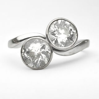 Stunning Antique 2 Stone Crossover Diamond Ring. This lovely 1920's crossover ring has two transitional brilliant cut diamonds in rub over settings. They are in an exquisite platinum shank. The total diamond weight is 1.6ct, the stones are VS1 in clarity and H-I in colour. Moi et Toi french for me and you is romantic centuries old jewellery style featuring two stones. This style of ring symbolises the union of two souls or the connection between two people. Please contact us if you would like to know more about this ring or visit us at Saddingtons Jewellery, Mayfair.