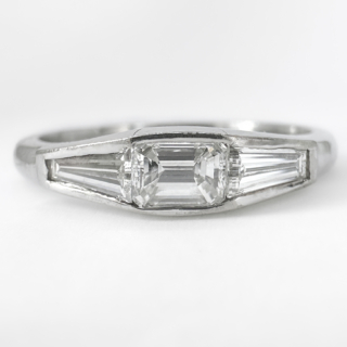 1960's Vintage 3 Stone Diamond Ring. This stunning ring features a center emerald cut diamond with tapered baguette diamonds on either shoulder. The diamonds are in a rub over setting, set in platinum. The center stone is 0.40cts and the diamonds either side are 0.20cts each. This ring is flattering and comfortable on the finger, it can be resized. Please contact us if you would like to know more about this ring or visit us at Saddingtons Jewellery, Mayfair.