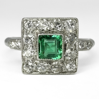Gorgeous Antique Emerald & Diamond Square Cluster Ring. This Edwardian square cluster ring has a center square vivid green columbian emerald surrounded by edwardian cut diamonds. The ring also has 2 edwardiand cut diamonds lining either shoulder. The stones sit in a pierced carved gallery and platinum shank. The ring sits low and comfortable on the finger. The top of the ring measures 9mm squared. This stunning ring can be resized. Please contact us if you would like to know more about this ring or visit us at Saddingtons Jewellery, Mayfair.