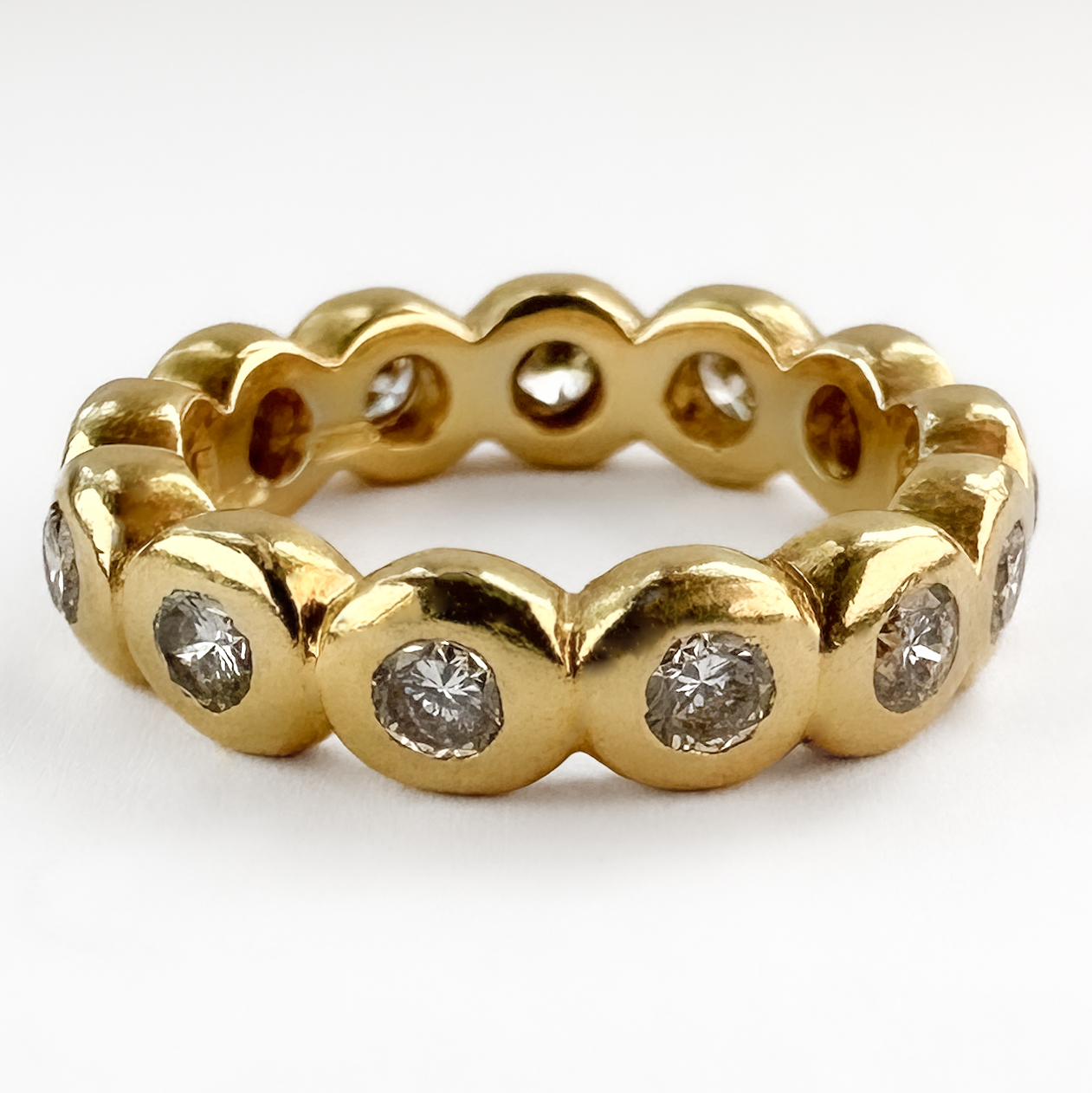 Sweet Diamond Rub Over Full Eternity Ring. A small but perfectly formed full circle of brilliant cut diamonds in a bubble like chunky 18ct yellow gold shank. The diamonds are H-I in colour and VS2 clarity. The total diamond weight is 0.40cts. The band features a London 1998 hallmark. Please contact us if you would like to know more about this lovely ring or visit us at Saddingtons Jewellery, Mayfair.
