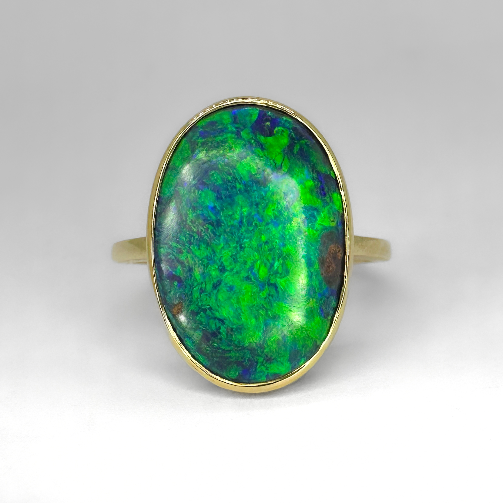 Vibrant Large Antique Oval Black Opal Ring Set In 18ct Yellow Gold. Stunning large Edwardian natural  black opal with stunning and vibrant green and blue hues. The opal measures 17mm x 11mm and is set in a rub over style ring mount. Beautiful polished yellow gold with a geometric gallery. An elegant and simple design showcasing the amazing black opal. The ring sits low and comfortable on the finger. It can be resized, please contact us if you would like more information on this ring.