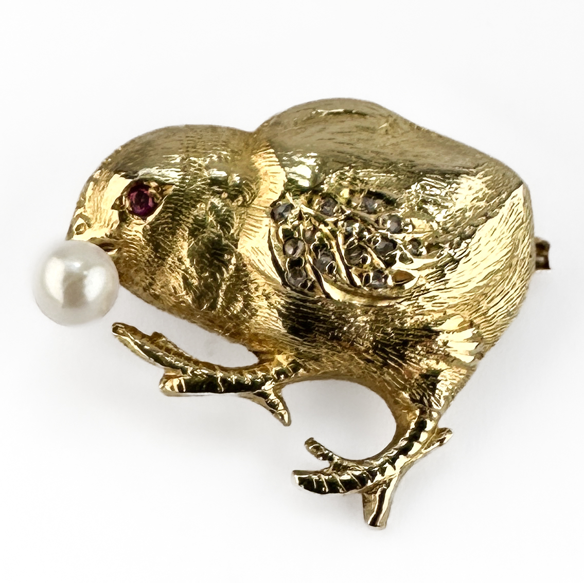 Vintage Gold Chick Brooch. Charming vintage 18ct gold chick brooch set with a pearl, ruby eye and diamond detail measuring 2x2.3cm.  Sweet small chick carrying a natural pearl in its beak, the brooch is crafted in richly textured 18ct gold with a lively sculptural finish. The brooch features a K18 stamp on the back. The eye is highlighted with a vivid ruby accent, while the wing is decorated with delicate diamond detailing adding subtle sparkle and refinement. Playful yet elegant, novelty animal brooches of this quality became highly fashionable during the 50s/60s and remain wonderfully collectable today. The brooch weighs 5.1g and comes in the box pictured. Please contact us if you would like to know more about this lovely brooch or visit us at Saddingtons Jewellery, Mayfair.