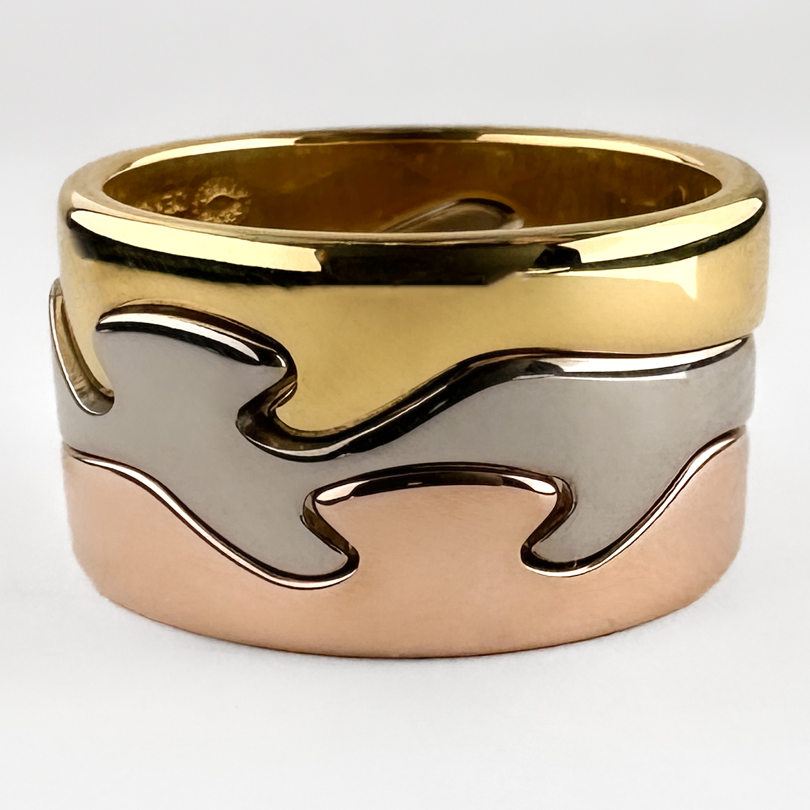 Georg Jensen Fusion 3 Ring Stack. This Iconic stack has 3 18ct gold tricolour bands that seamlessly interlock. The organic wave like bands 'fuse' together to create a contemporary and interesting design. These rings were designed by Nina Koppel who was commissioned by Georg Jensen. All 3 bands feature full Georg Jensen hallmarks including a Denmark stamp, N K stamp and 750 gold stamp. These yellow, rose and white gold rings can be worn together or separately. Please contact us if you would like to know more about this beautiful ring stack or visit us at Saddingtons Jewellery, Mayfair.