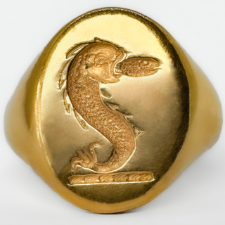 A Striking And Substantial Vintage Nautical Crest Intaglio Signet Ring. In 18ct yellow gold dating to the 1980s, and distinguished by a finely carved intaglio crest of likely nautical inspiration. Crafted in rich yellow gold and weighing an impressive 15 grams, this is a piece that carries immediate presence on the hand — a true statement signet ring in the traditional sense. The intaglio carving, cut in reverse as a seal, evokes the long-standing heritage of signet rings as markers of identity, authority, and lineage. The crest itself suggests maritime or naval associations, lending the ring a sense of story and potential provenance beyond its already strong aesthetic appeal. Whether originally commissioned as a personal seal or later acquired for its symbolism. Ideal for a collector of unusual signet rings, or a buyer seeking a piece with individuality and depth, this ring sits comfortably between traditional gentleman’s jewellery and contemporary statement wear. A rare opportunity to acquire a heavily weighted, intaglio-carved gold signet ring with both decorative and symbolic appeal. Please contact us if you would like to know more about this wonderful ring or visit us at Saddingtons Jewellery, Mayfair.