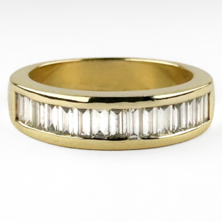 Channel Set Baguette Diamond Ring. A sleek and elegant channel set diamond ring crafted in rich 18ct yellow gold and fully hallmarked for Edinburgh, 2005. Inside the band is also an 'MS' makers mark, a '750' gold mark and a '0.75ct' diamond weight mark. The ring is set with a continuous row of 15 baguette cut diamonds totallling 0.75cts in a refined channel setting, creating a clean and sophisticated line of brilliance across the finger. The geometric baguette cuts give the ring a distinctly timeless and architectural feel, beautifully balanced by the warmth of the polished yellow gold mount. Comfortable and highly wearable, this piece works effortlessly as a wedding band, eternity ring, stacking ring, or understated everyday diamond piece. Its minimalist design allows the quality of the diamonds and craftsmanship to speak for themselves, making it an enduring classic with contemporary appeal. A versatile and elegant diamond ring with crisp sparkle and a luxurious, substantial feel. Please contact us if you would like to know more about this gorgeous ring or visit us at Saddingtons Jewellery, Mayfair.