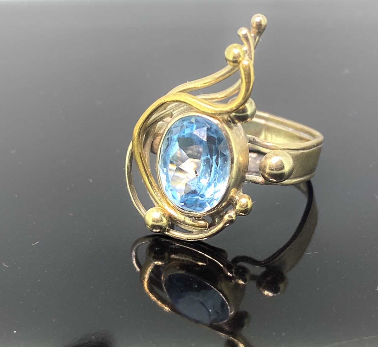 Vintage Blue Topaz Swirl Ring in hallmarked 9ct gold. This stunning, flowing ring design has a makers mark also PJC and hallmarked Birmingham 1989. The central blue topaz is faceted and has a light to mid blue topaz. The ring can be resized free
