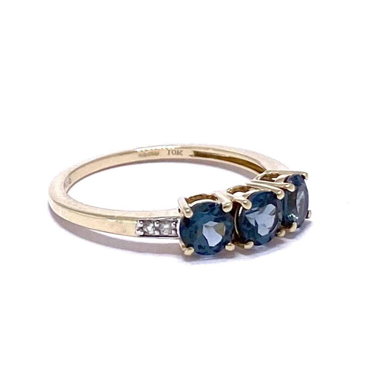 The 3-Stone London Blue Topaz Half Eternity Stacking Ring is 9ct Gold. The ring has three 4-prong set, brilliant cut, deep turquoise blue Topaz. Both shoulders are flush set with two white micro Diamonds