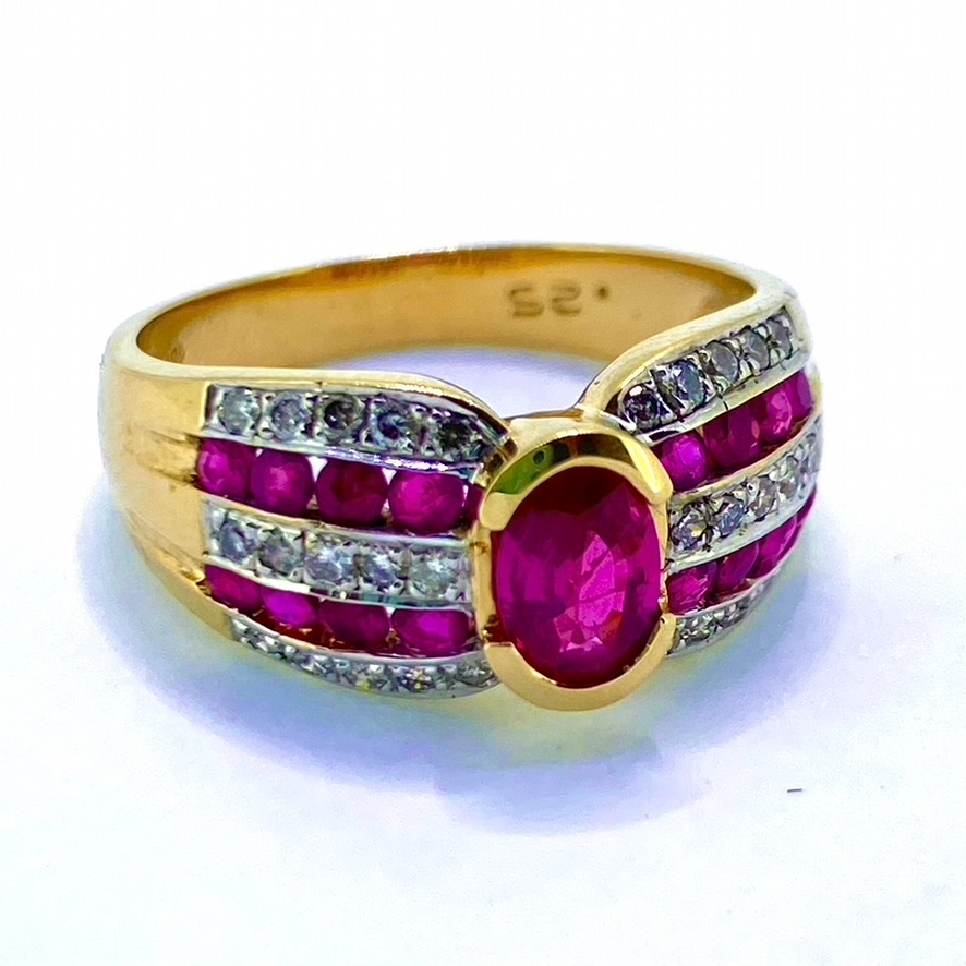 Ruby and Diamond Stylised Ring, Hallmarked London 375 (for 9ct gold). The head of the ring holds one central faceted ruby measuring 7mm X 4mm, surrounded by 16 channel set rubies and 35 grain set diamonds. 